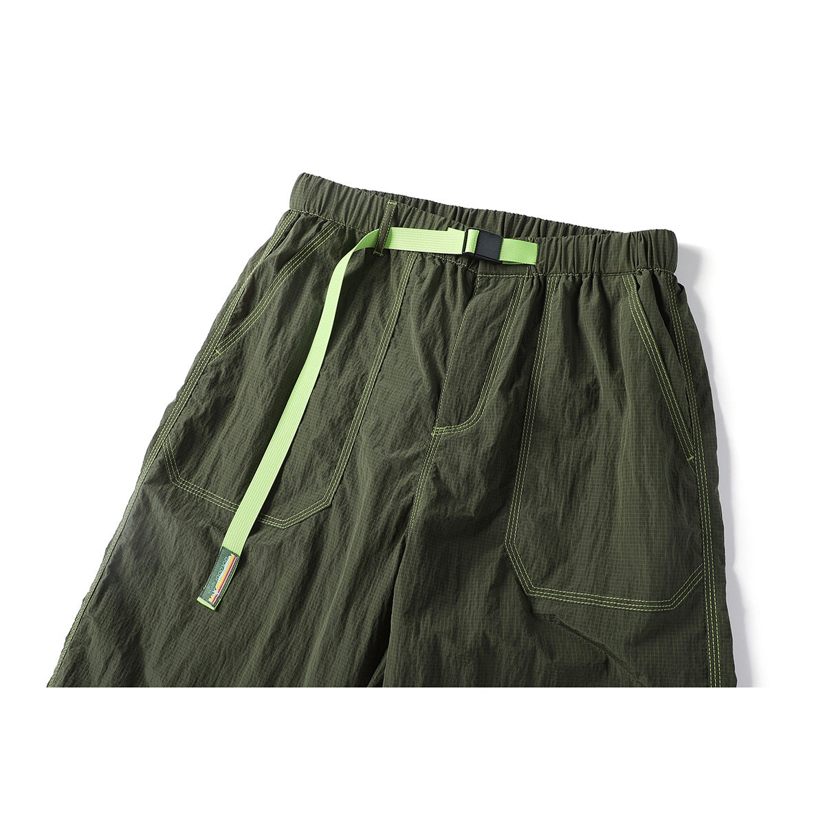 Front view of dark olive cargo-style pants with a lime belt, elastic waist, large pockets and contrast stitching.