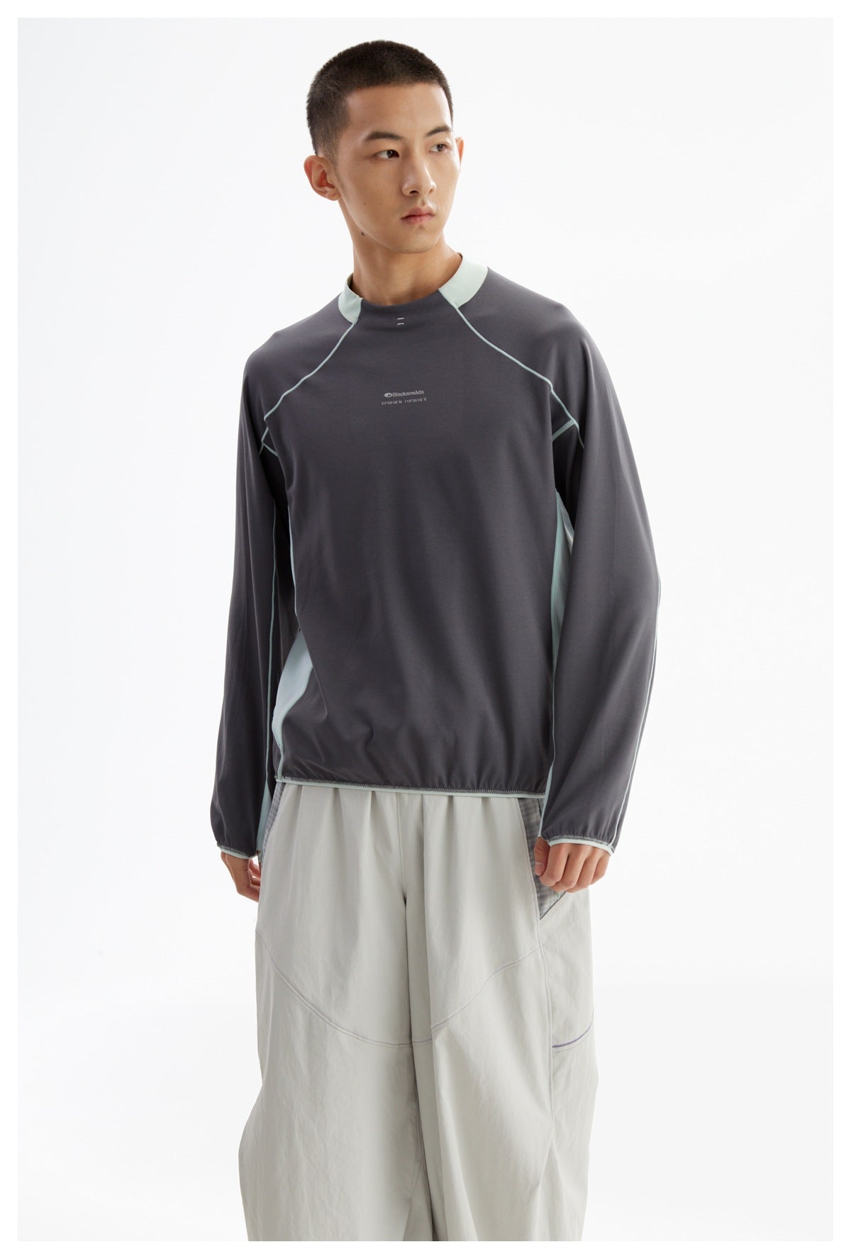 Front view of a model wearing a charcoal long-sleeve top with pale mint collar and piping, paired with light gray pants.