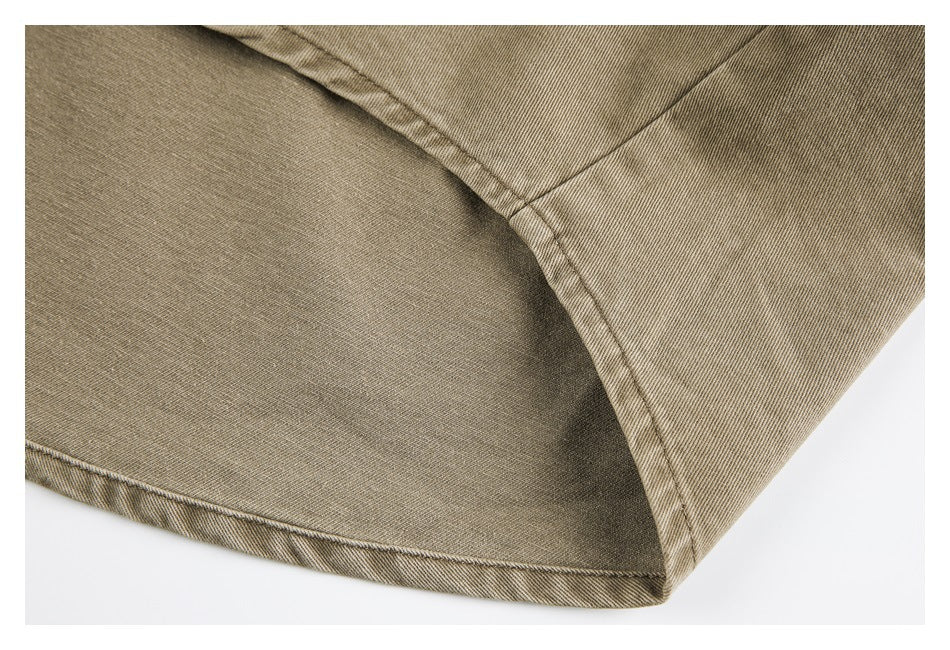 Close-up of the curved hem and stitched seam on a tan shirt.