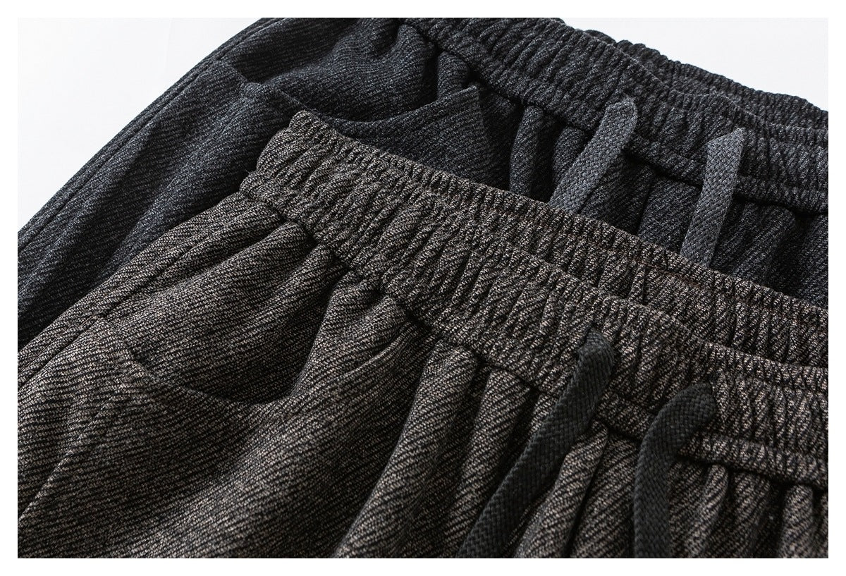 Close-up of brown and charcoal trousers with elastic waistbands and dark drawstrings.