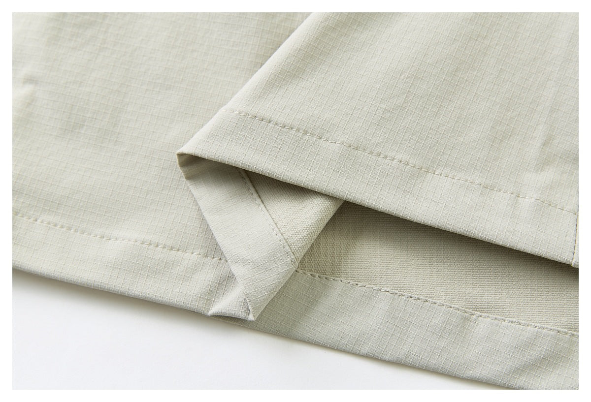 Close-up of the pale khaki garment hem, showing folded fabric layers and rows of stitching.