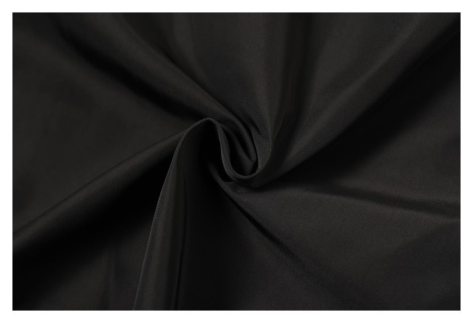 Close-up of black fabric gathered into a soft spiral, showing its fine surface texture.