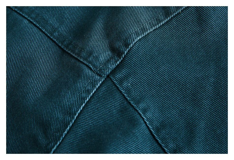 Close-up of dark teal fabric with diagonal seams and a fine ribbed texture.