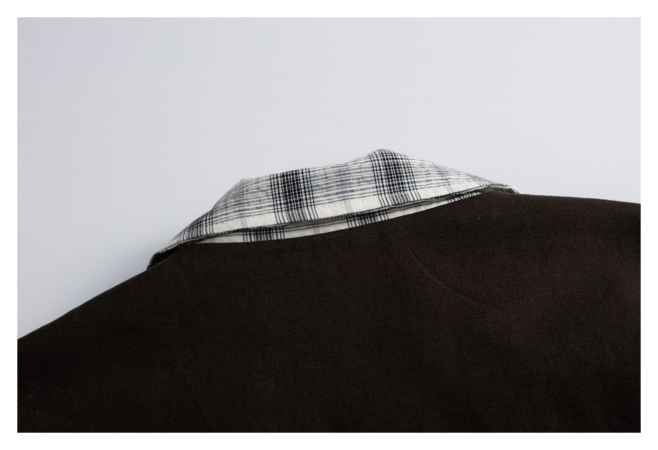 Close-up of the jacket's dark back panel with a small section of cream plaid collar visible.