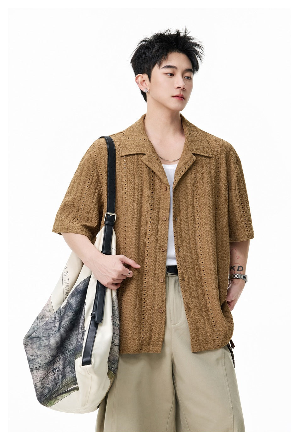 Model in a brown open-front camp-collar shirt over a white tank, close-up with a tote bag