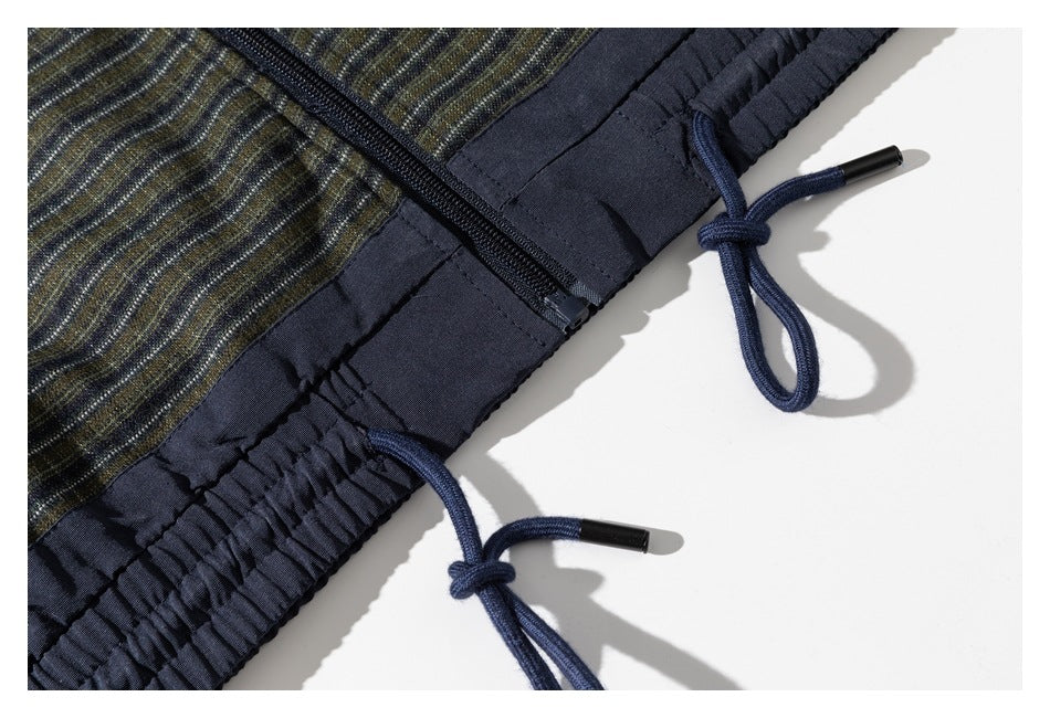 Close-up of the jacket’s navy gathered hem, zipper, and adjustable drawcords.