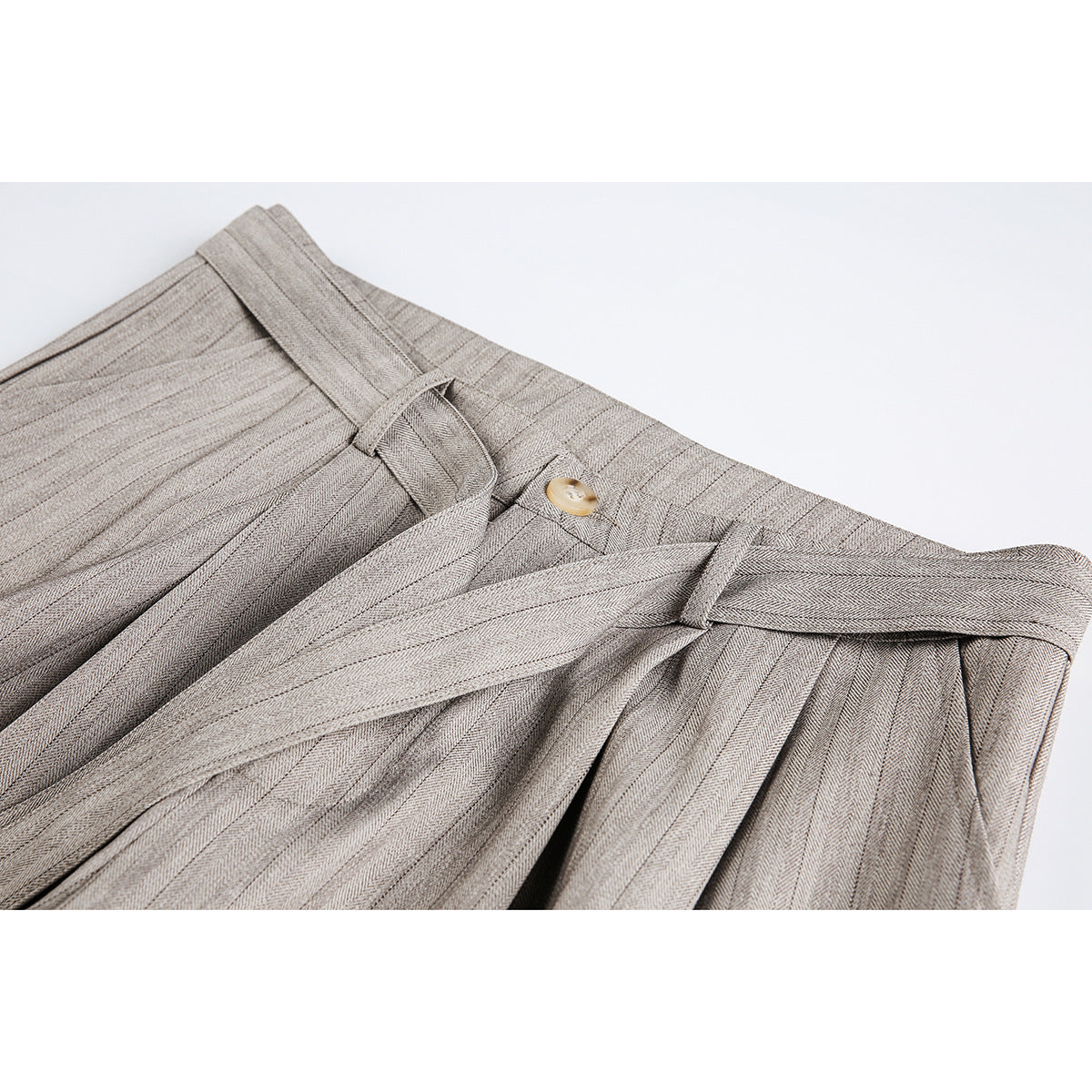 Close-up of taupe-gray pinstriped trousers showing pleats, belt loops, button, and long waist ties.