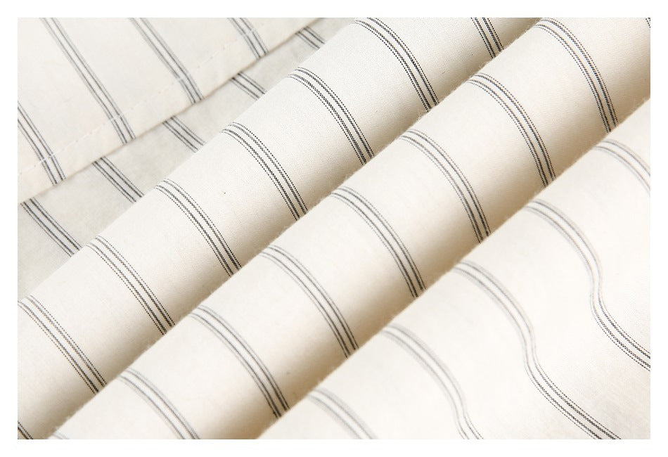 Close-up of softly folded off-white fabric with repeating thin dark stripe bands.