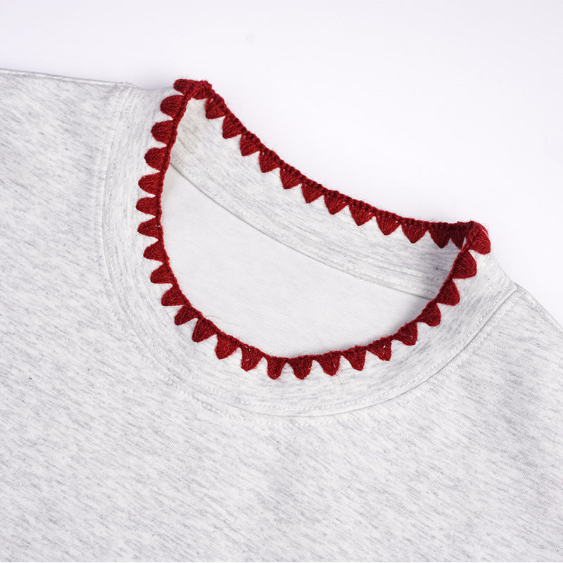 Close-up of a light gray T-shirt neckline with dark red scalloped trim.
