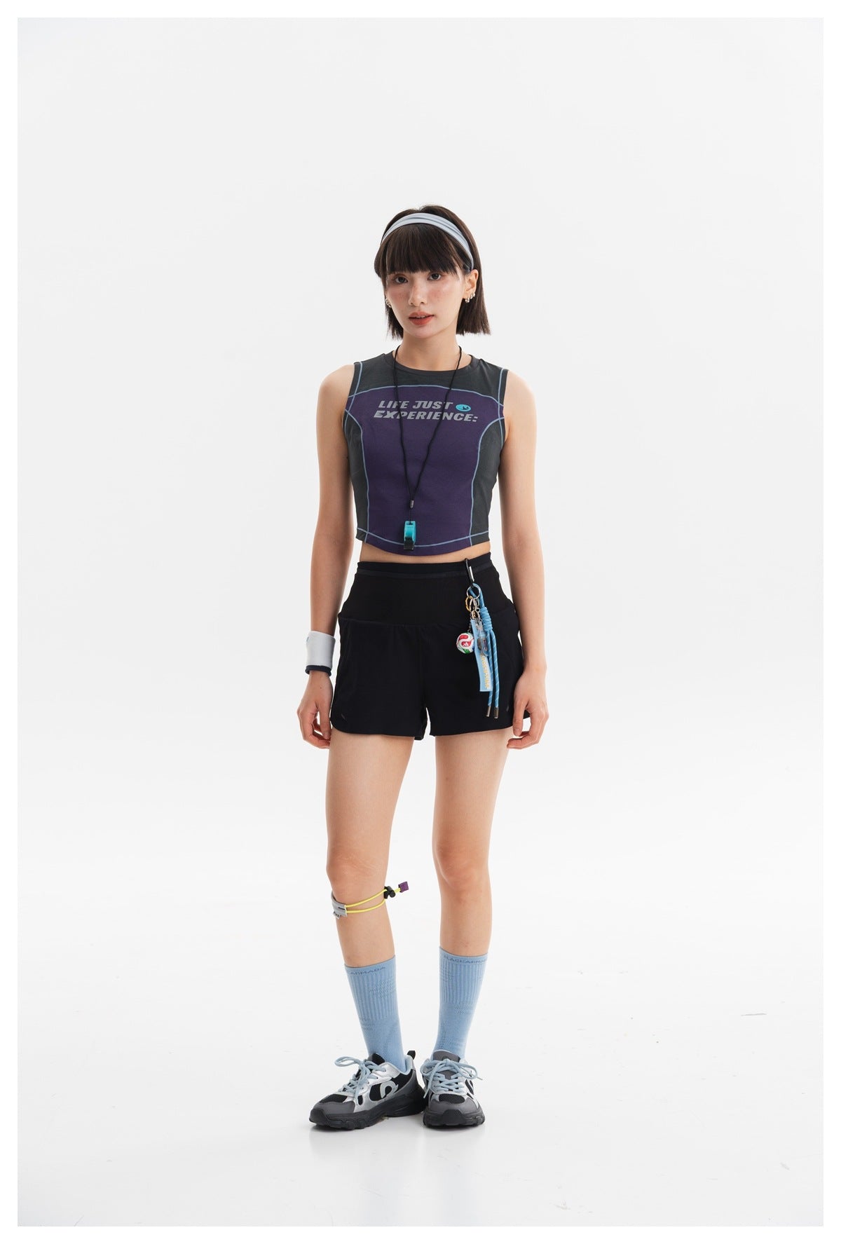 Model wearing a purple and charcoal sleeveless crop top with black shorts.