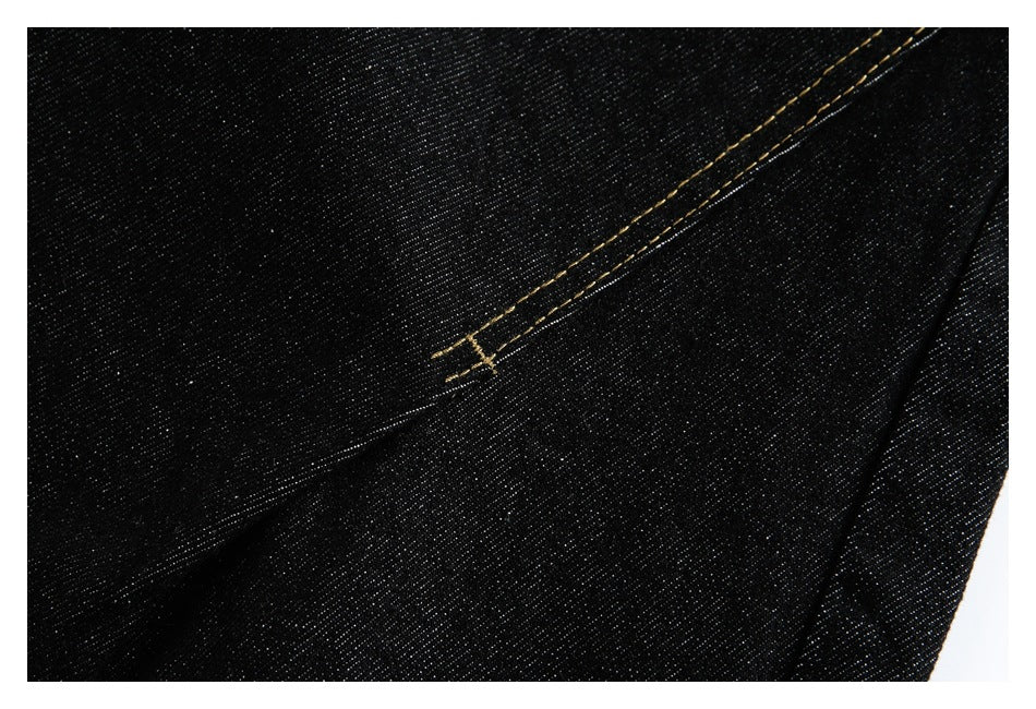 Black denim close-up showing a diagonal seam with golden stitching.
