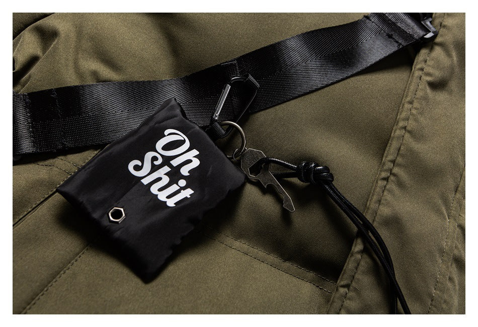 Close-up of an olive jacket with a black strap, clips and a pouch marked “Oh Shit.”