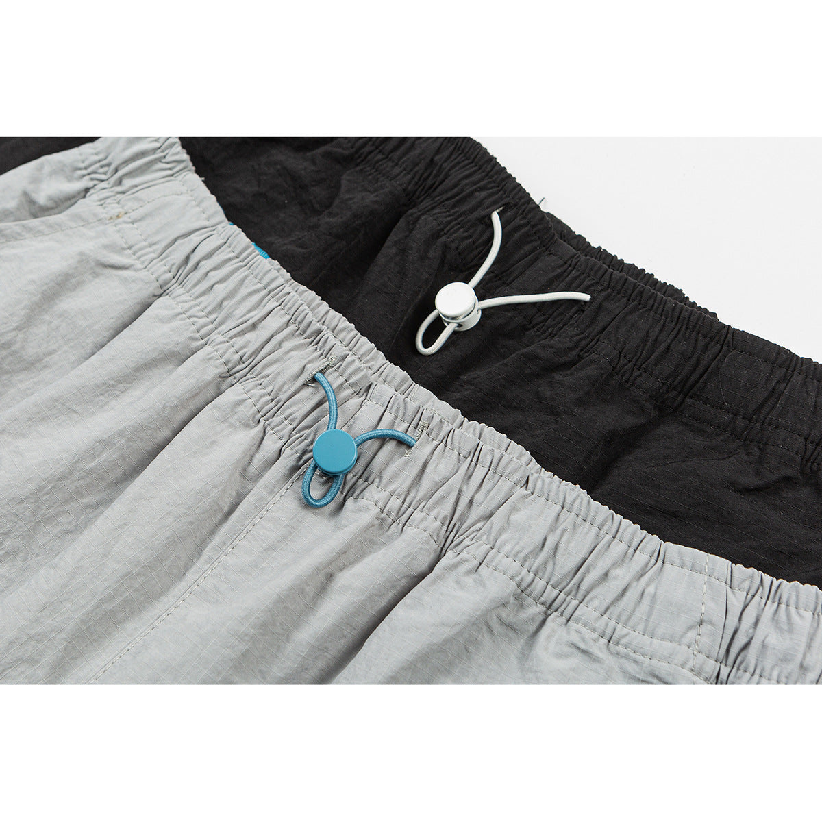 Close-up of gray and black shorts with elastic waistbands and adjustable drawcords.