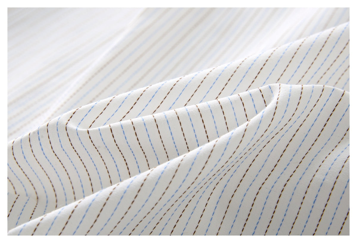 Close-up of folded white fabric with fine blue and brown dashed stripes.