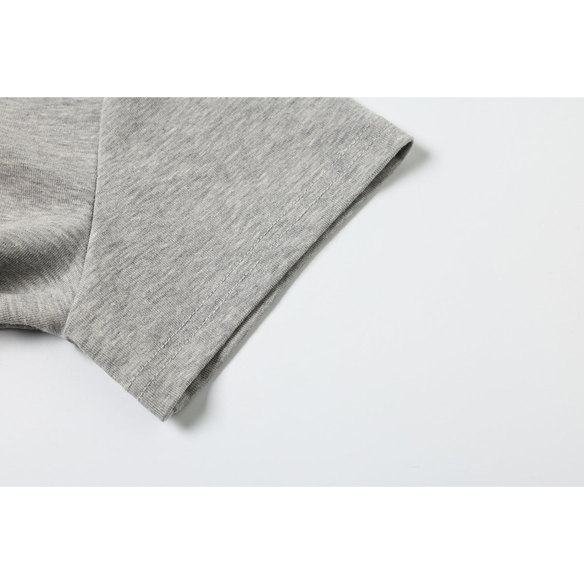 Close-up of the double-stitched sleeve hem on a heather gray T-shirt.
