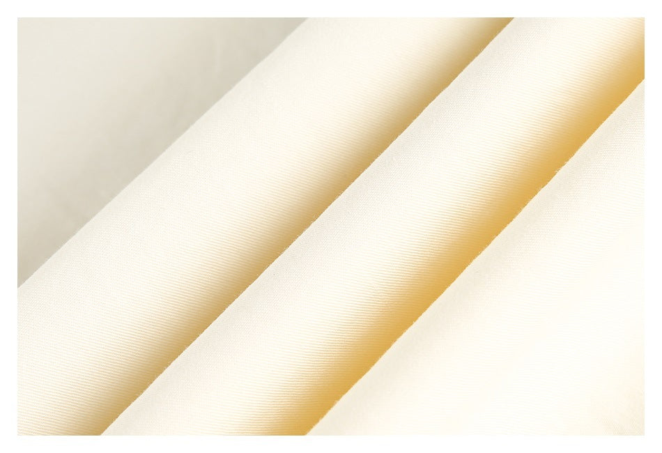 Close-up of ivory fabric arranged in diagonal folds, showing its fine surface texture.