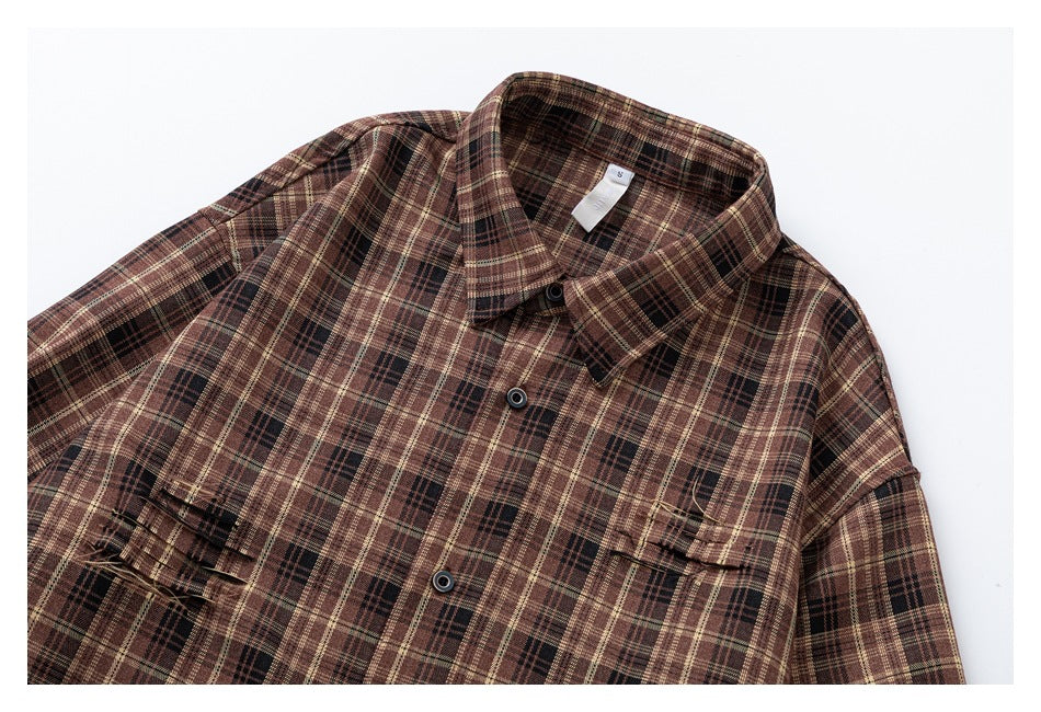 Angled close view of a brown plaid button-up shirt front with a pointed collar and chest pockets.