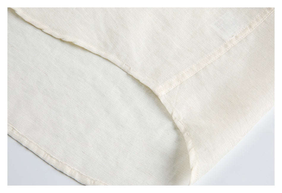 Close-up of an ivory shirt showing a curved seam and double-stitched edge.