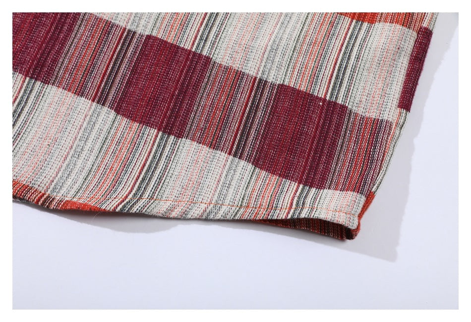 Close-up of the plaid shirt's curved hem and stitched edge against a white background.