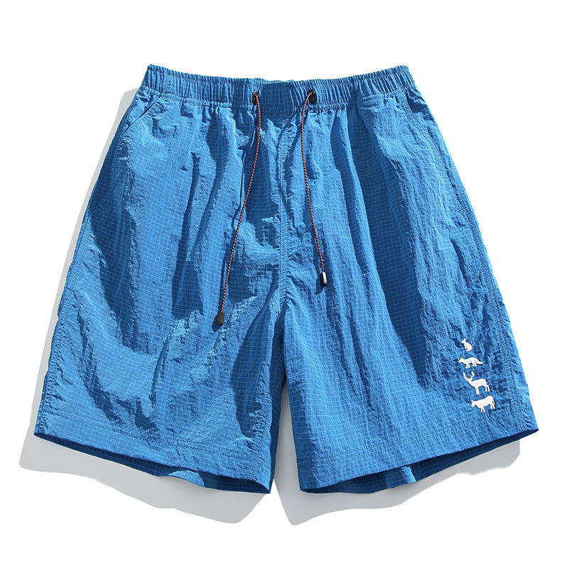 Bright blue textured drawstring shorts with grid pattern and white animal embroidery near the hem, flat lay
