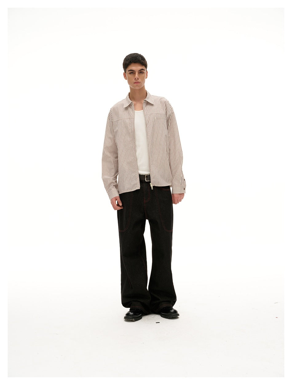 Model wearing open beige striped zip shirt over a white tank top with black wide-leg jeans, front view