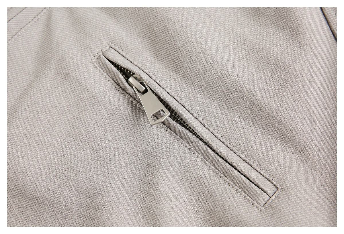 Close-up of a diagonal metal zipper pocket on light taupe fabric.