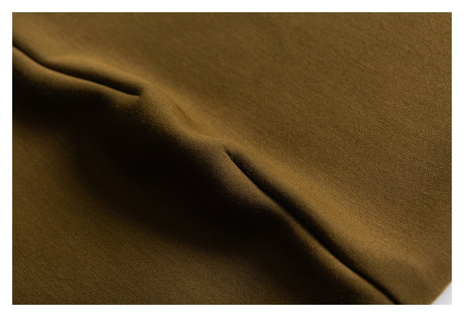 Close-up of ochre fabric folds and a stitched seam.