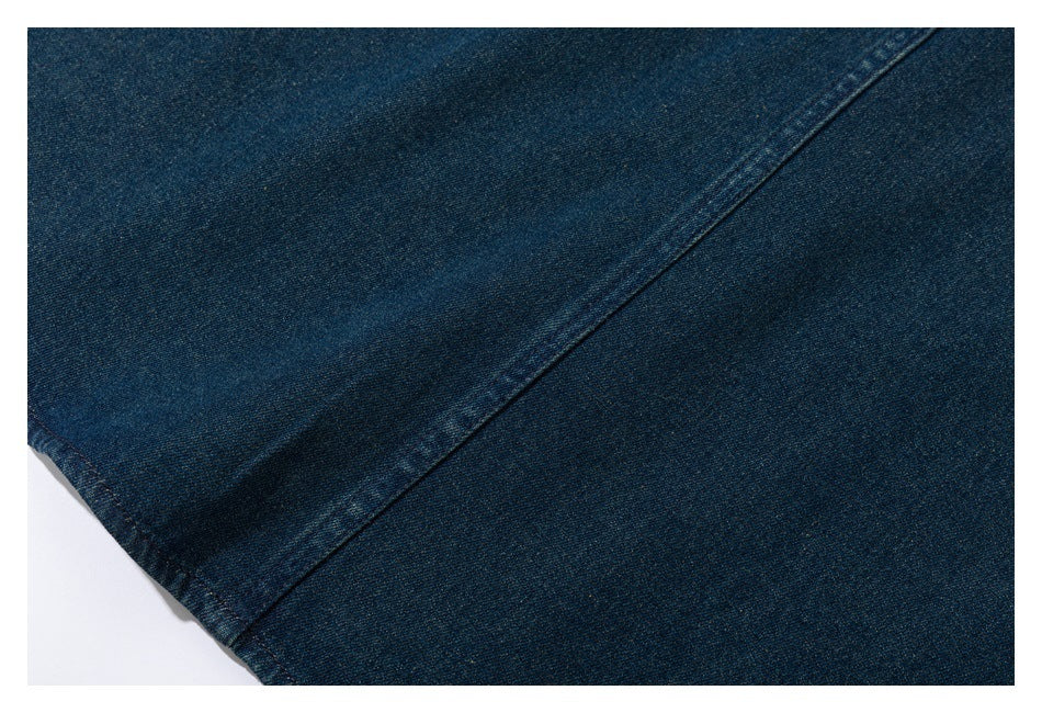 Close-up of dark blue denim with a diagonal seam and visible stitching.