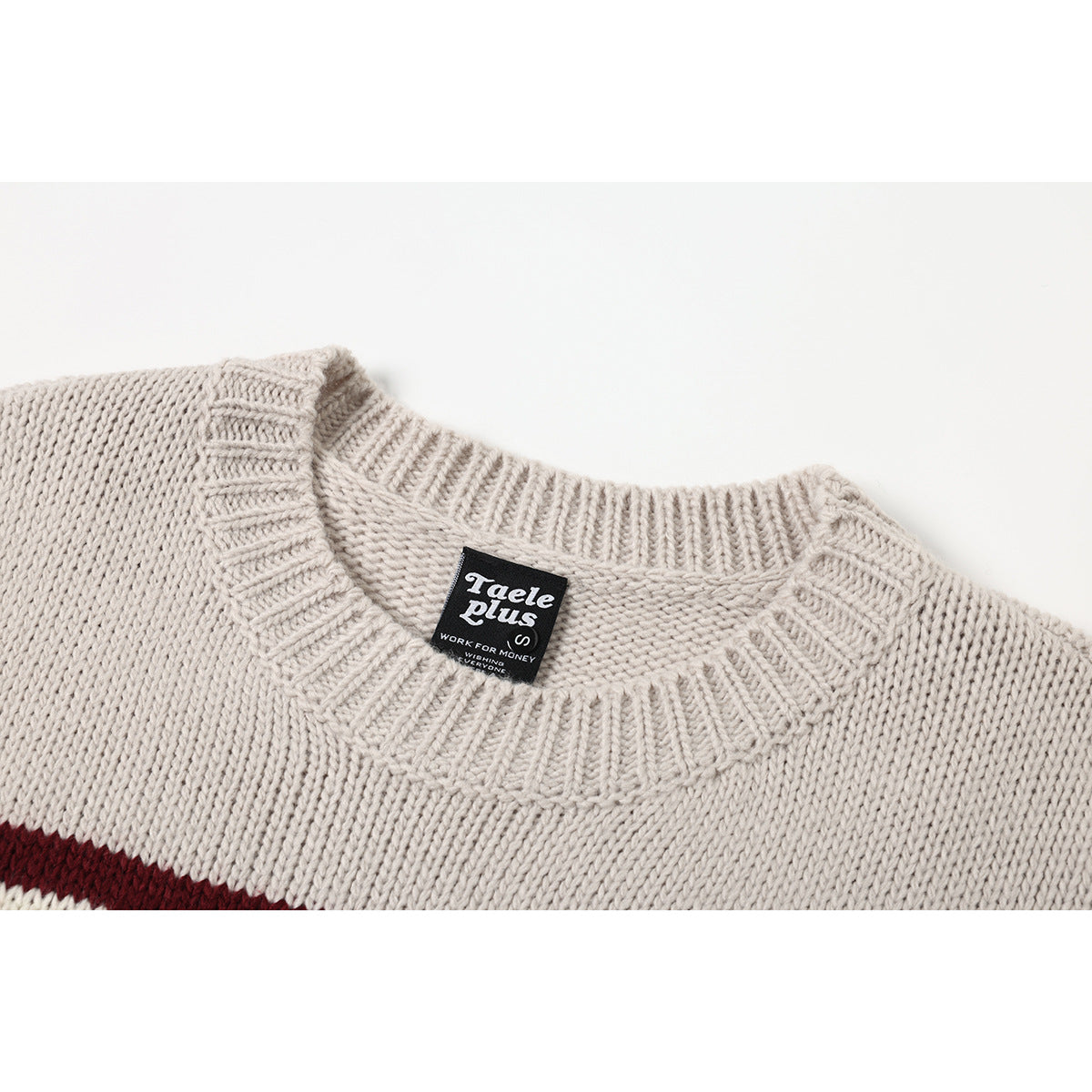Close-up of a cream knit sweater's ribbed crew neck and sewn-in black neck label.