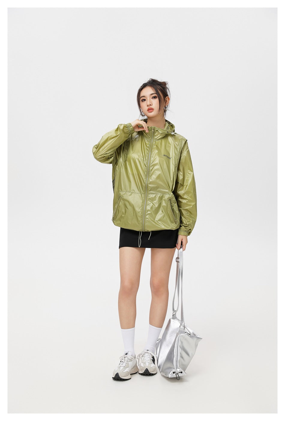 Model wearing an olive hooded jacket zipped at the front, with zip pockets and elastic cuffs.