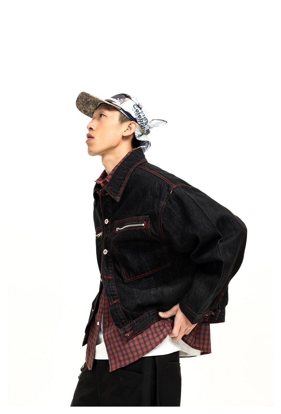 Closer angled view of a model wearing a black jacket with red stitching, silver buttons, and a zippered chest pocket.