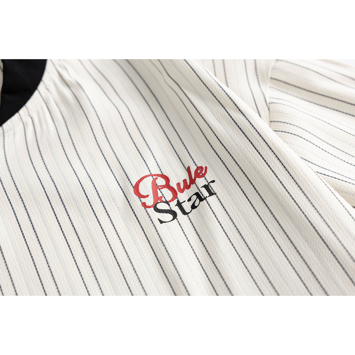 Close-up of a cream pinstriped jacket showing red-and-black chest lettering.