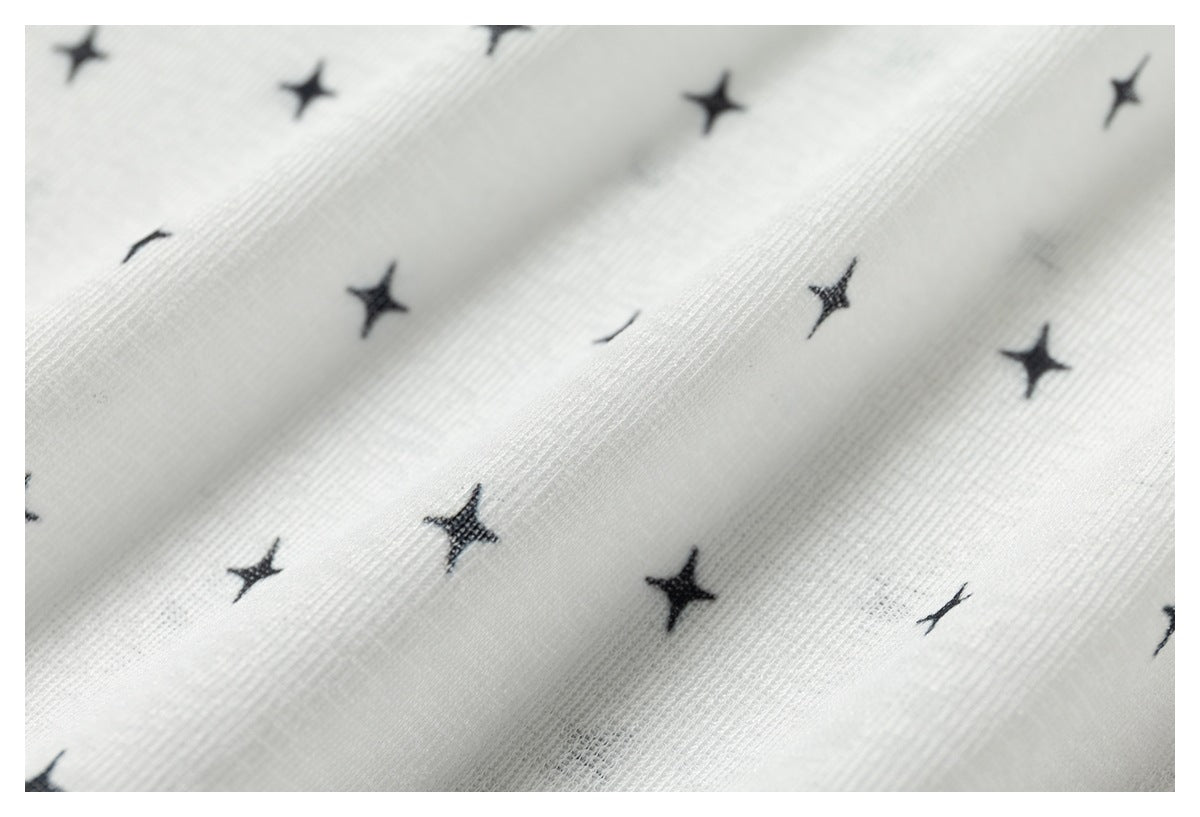 Macro view of white knit fabric printed with small black stars.