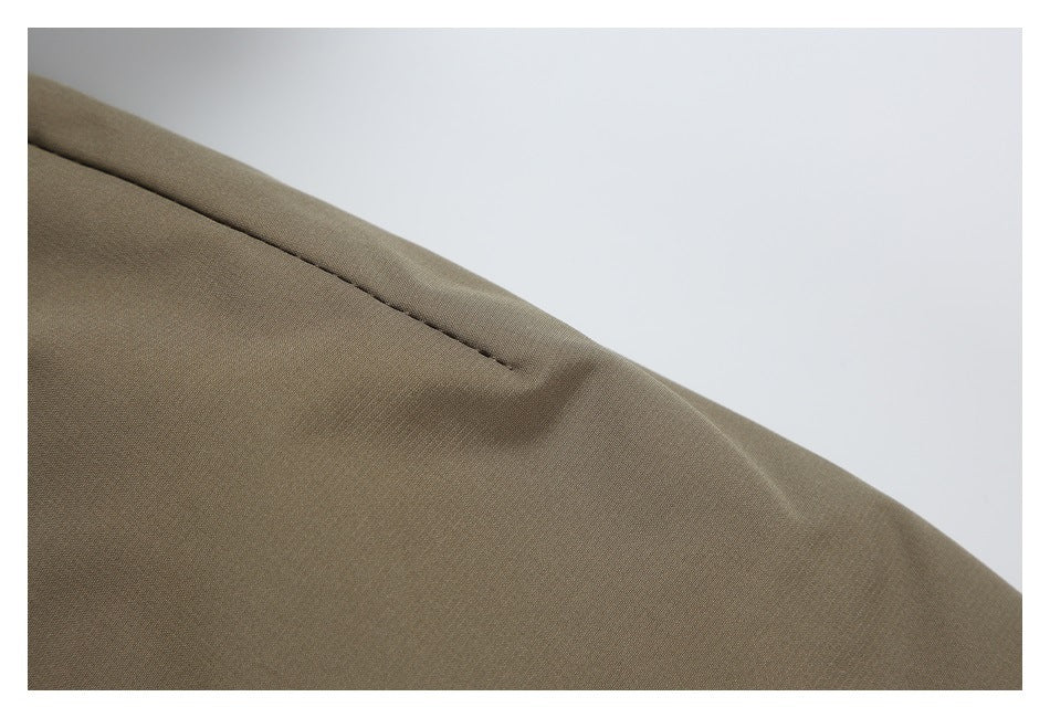 Close-up of a taupe-brown jacket sleeve seam and smooth fabric surface.