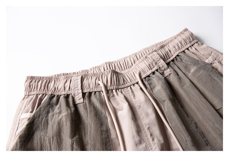 Close-up of pale beige shorts showing the elastic waistband, drawstrings, and contrasting crinkled gray panels.