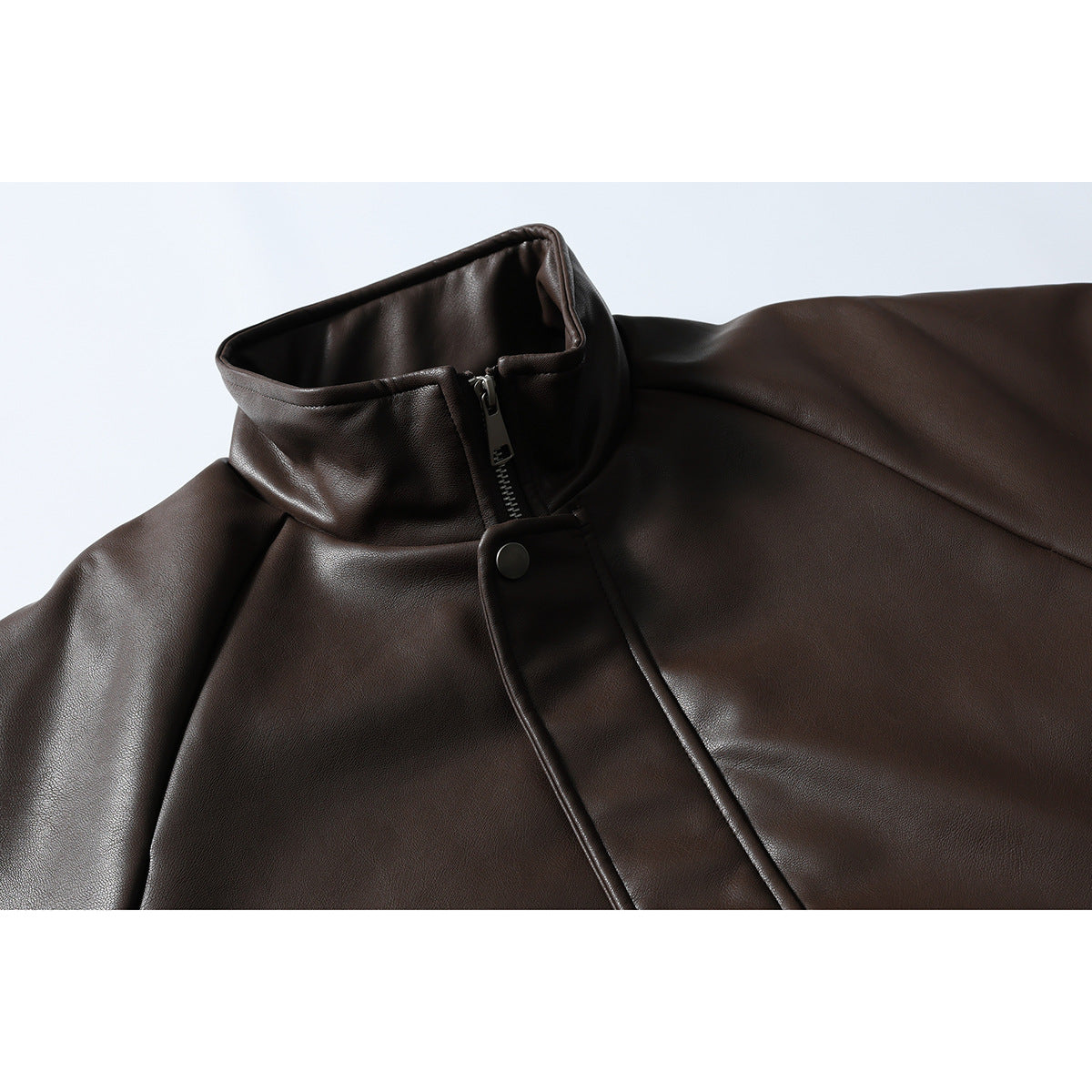 Close-up of a dark brown jacket's stand collar, zipper, and snap-button storm flap.