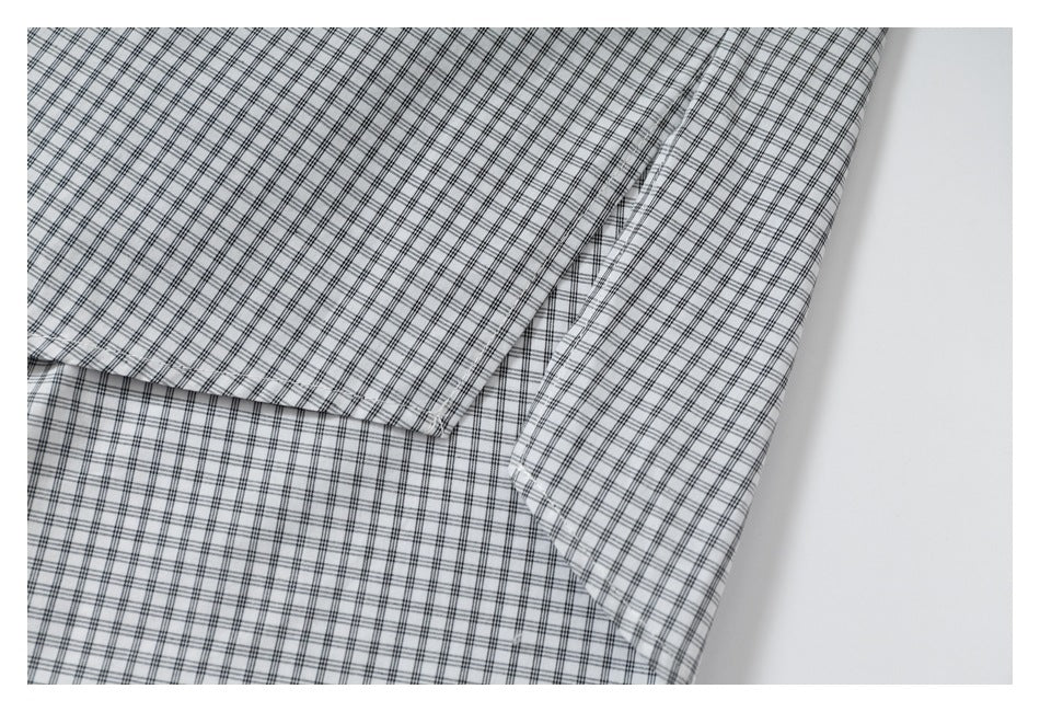 Close-up of folded black-and-gray checked shirt fabric with overlapping panels and stitching.
