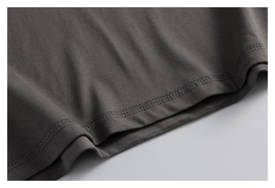 Close-up of the dark charcoal garment hem with visible overlock stitching and folded fabric.