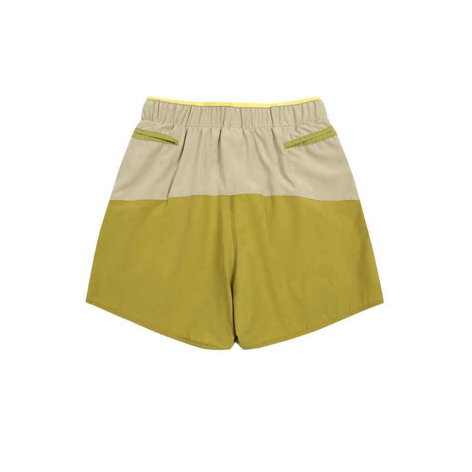 Back view of two-tone shorts in mustard yellow and pale beige, with an elastic waist and two rear pockets.