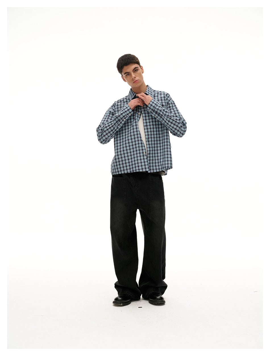 Model wearing a blue plaid shirt with hands at the collar, over a white tank top and black wide-leg jeans
