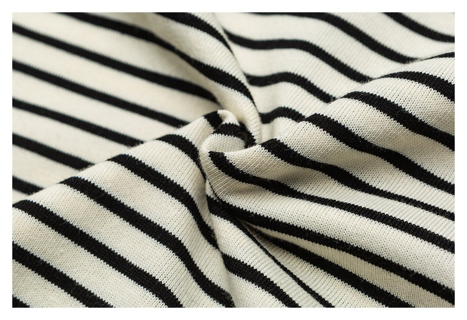 Close-up of cream fabric with narrow black stripes gathered into soft folds.