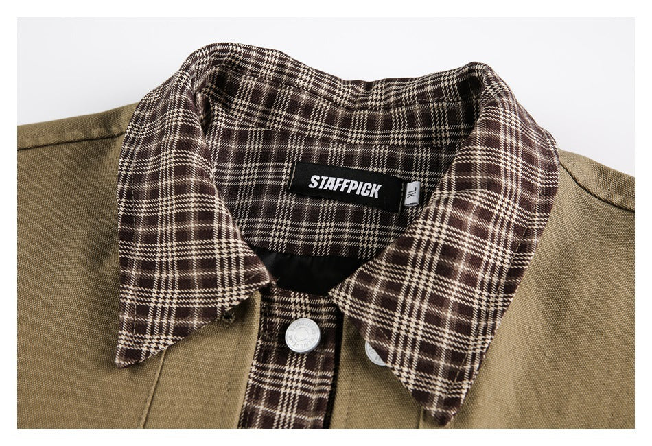 Close-up of a khaki overshirt's brown plaid collar, front placket, and sewn-in neck label.