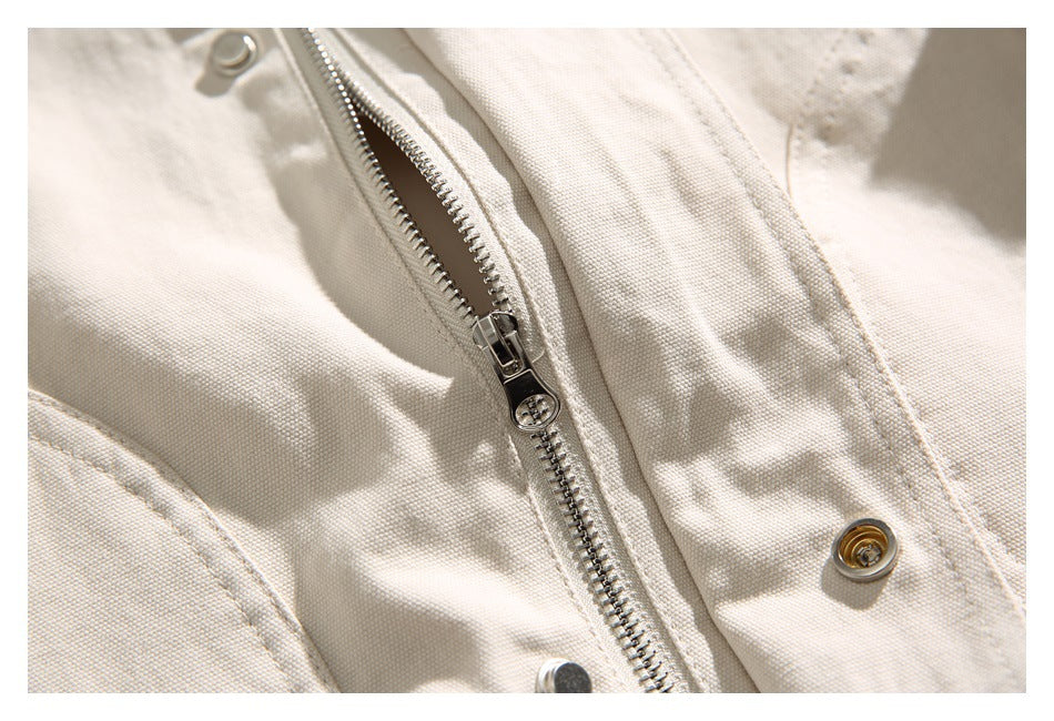 Close-up of an ivory jacket's metal zipper, snap fasteners, and stitched front panel.