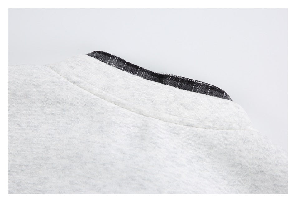 Close-up of a light gray marled garment neckline with dark patterned inner trim.