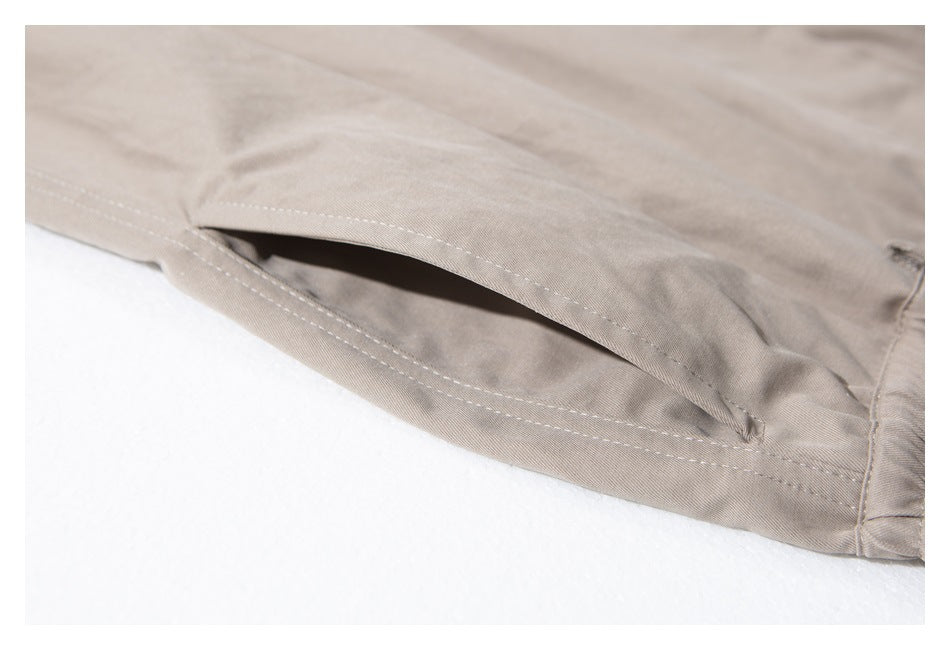 Close-up of a slanted side pocket with visible stitching on taupe trousers.