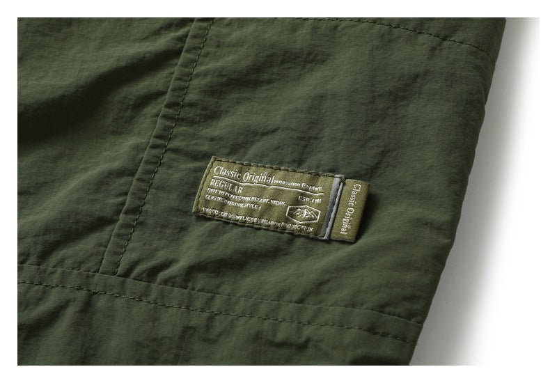 Close-up of a dark olive garment with a sewn label bearing small English text and a mountain icon.