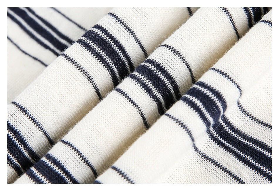 Close-up of folded cream knit fabric showing navy stripe bands and knit texture.
