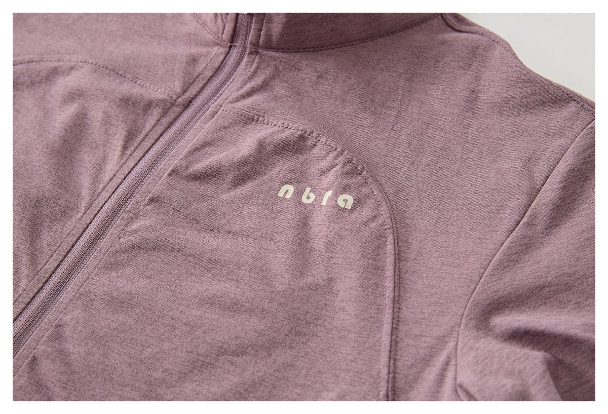 Close-up of the mauve top's zipper, curved seam, and small pale chest lettering.