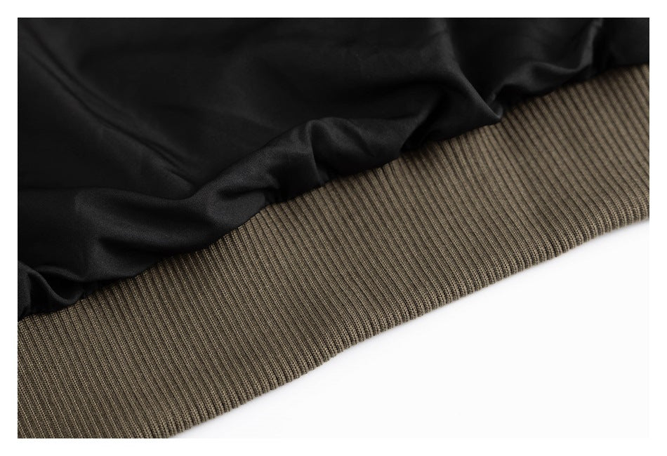 Close-up of a black jacket body meeting a wide olive-brown ribbed hem.