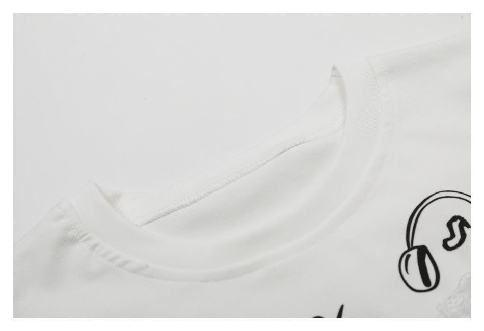 Close-up of a white T-shirt's ribbed crew neckline and part of its black music-themed print.